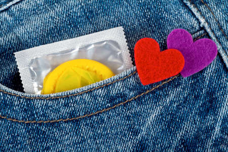 Condom in blue jeans pocket and colored heartsの写真素材