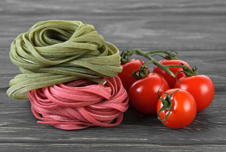 Colorful italian pasta and cherry tomatoes on wooden tableの写真素材