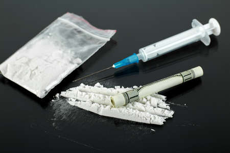 Syringe for heroin and cocaine powder on black background, drug abuse concept.の写真素材