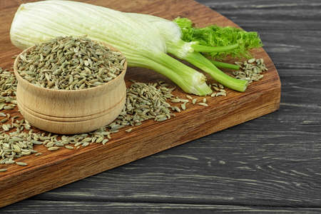 Ripe fennel bulb and dry seeds in bowl on wooden table
