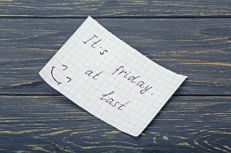 Inscription on paper it's friday at last on a wooden board
