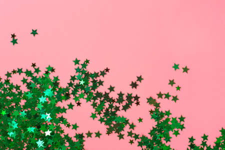Green glitter stars on pink background. Festive holiday pastel backdrop.の写真素材