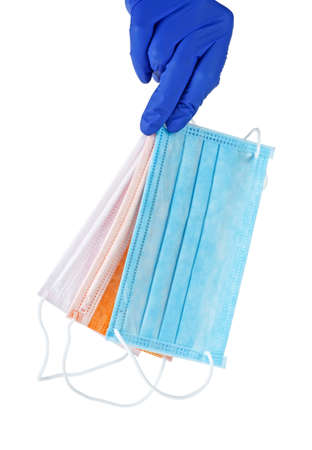 Hand in blue glove holds a colored medical face masks against viruses and bacteria on a white background. Protective medical tool.
の写真素材