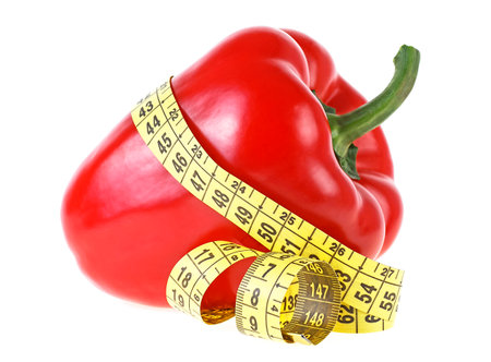Red sweet bell pepper and yellow measuring tape isolated on a white background. Healthy food and diet concept.の写真素材