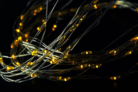 Abstract Christmas lights on a black background. Glowing light bulb garland. Selective focus.の写真素材