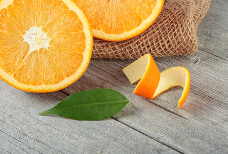 Orange fruit with orange peel and green leaf on wooden table. Healthy food.の写真素材