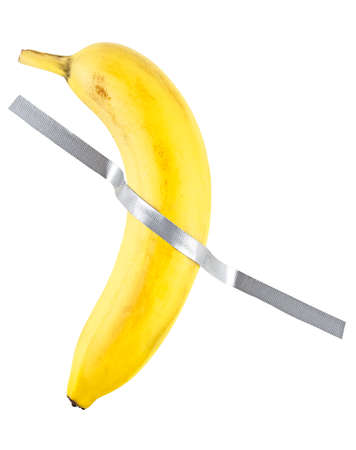 Banana duct taped to the white wall. Yellow banana on the white wall.の写真素材