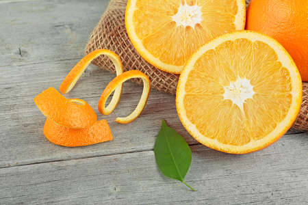 Orange fruit with orange peel and green leaf on wooden table. Healthy food.の写真素材