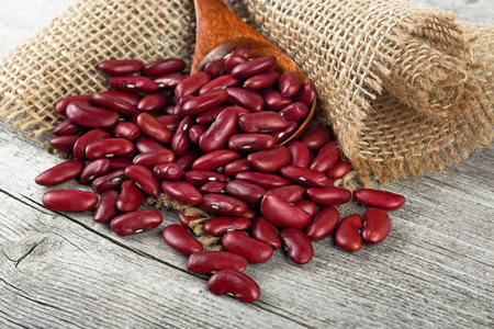Red kidney beans in wooden spoon on gunny bag and wooden table