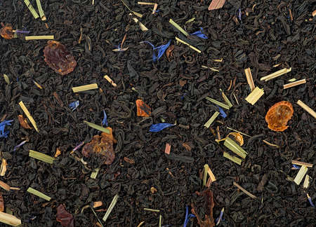 Black tea scented with fruits and flowers, top view. Dried black tea as background.の写真素材