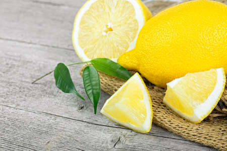 Fresh lemons, lemon slices and lemon leaves on rustic wooden background. Fresh citrus fruit.の写真素材