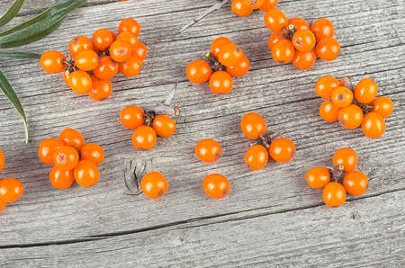 Sea buckthorn berries with leaves on wooden background, top view.の写真素材