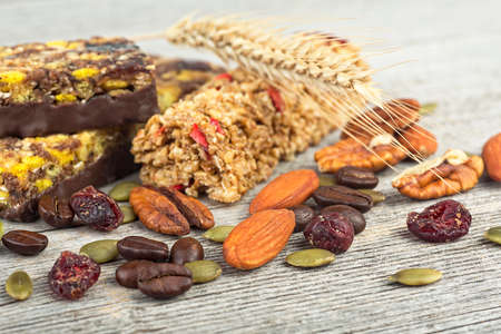Healthy cereal bars with granola, nuts, dried fruits and coffee beans on a wooden backgroundの写真素材
