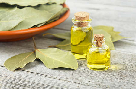 Natural bay laurel essential oil in glass bottles with dried leaves on a wooden table. Healthy lifestyle and beauty concept.の写真素材