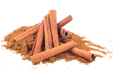 Pile of cinnamon powder and aromatic cinnamon sticks isolated on a white backgroundの写真素材