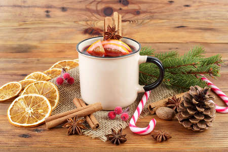 Delicious Christmas hot mulled wine, green pine tree branch and spices on wooden background.の写真素材