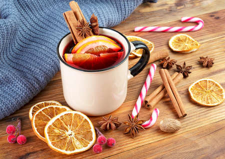 Delicious Christmas hot mulled wine, wool scarf, candy Christmas cane and spices on wooden background.の写真素材