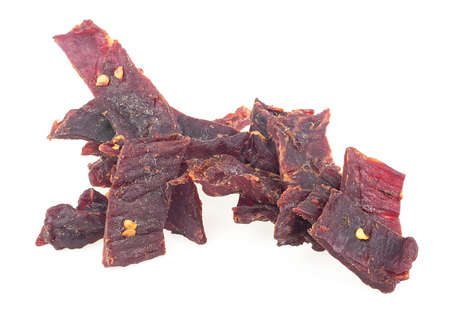 Pile of dried and spiced beef jerky pieces isolated on a white backgroundの写真素材