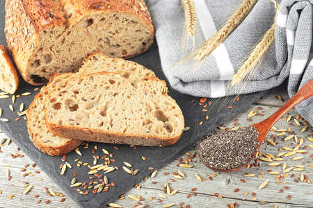 Freshly baked traditional sliced rye bread on black board. Whole grain rye bread with seeds and...