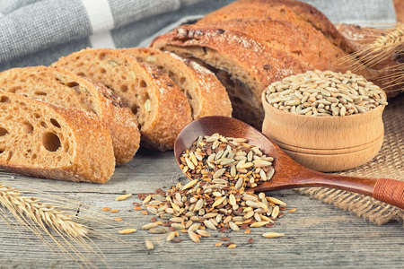 Freshly baked rye baguette on wooden table. Whole grain rye baguette with seeds and spikelets.の写真素材
