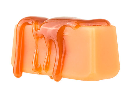Caramel sauce flowing on caramel candy, isolated on a white background. Levitating caramel candy.の写真素材