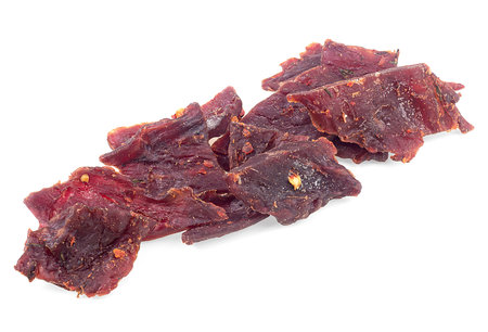 Dried and spiced beef jerky pieces isolated on a white backgroundの写真素材
