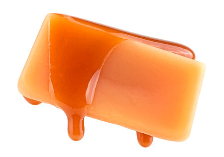 Caramel sauce flowing on caramel candy, isolated on a white background. Levitating caramel candy.の写真素材