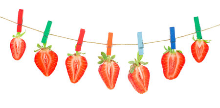 Garland of red ripe strawberries hanging on wooden clothespins on rope, white background.の写真素材