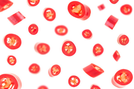Falling sliced red hot chili peppers isolated on a white background, selective focus.の写真素材