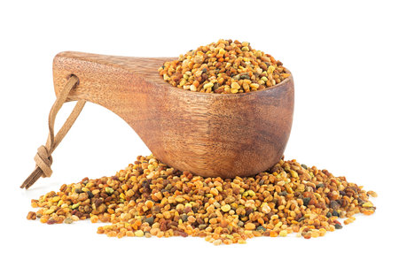 Organic bee pollen in wooden spoon isolated on a white background, healthy food supplements. Dried healthy natural honey bee pollen. Ambrosia.の写真素材