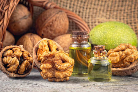Walnut kernels, whole walnuts and bottles of essential nut oil on rustic old wooden table. Fresh and healthy walnuts.の写真素材