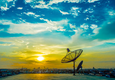 satelite dishes with sunset and city backgroundの写真素材