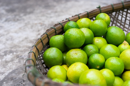 Fresh green limes in wooden basket for sell at the marketの写真素材