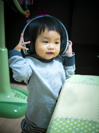 asian little girl use headphone in bedroomの写真素材