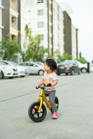 Little girl learns to riding balance bike on the roadの写真素材