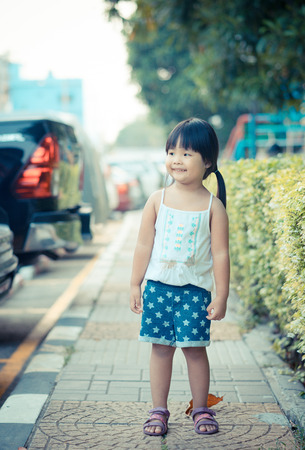 portrait of happy little girl standing in the parkの写真素材