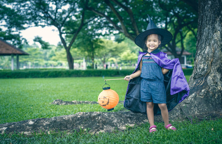 Little girl in a witch costume holding a lamp in halloweenの写真素材