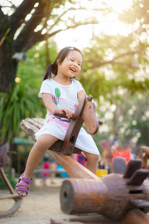 Asian little girl having fun on seesaw at playgroundの写真素材
