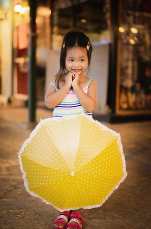 little girl with umbrella in the market on raining dayの写真素材