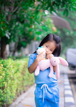 Cute little asian girl with a doll in the parkの写真素材