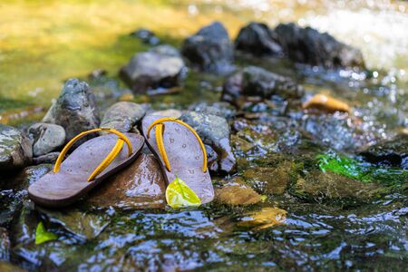 Slippers were placed on the rock in the waterの写真素材