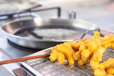 Deep fried dough sticks on steel net for sell with pan backgroundの写真素材
