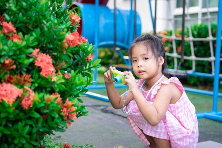 Portrait of cute little asian girl have fun with toy camera in the parkの写真素材