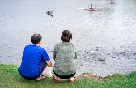 asian senior couple have activity together, feeding fish at the pondの写真素材