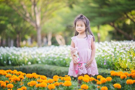 Cute little asian girl with a doll in the gardenの写真素材