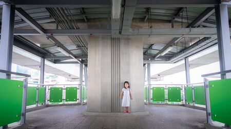 Portrait of happy little girl on elevated pedestrian walkway over traffic road