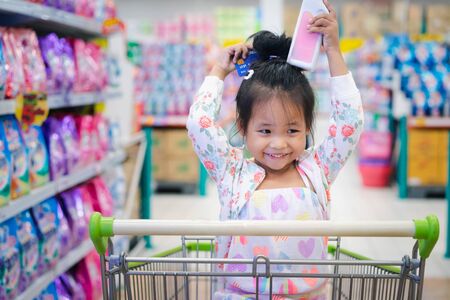 little girl sitting in the cart between shopping with credit cardの写真素材