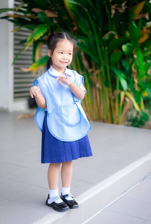 Portrait of happy little girl in Thai school uniform standing at schoolの写真素材