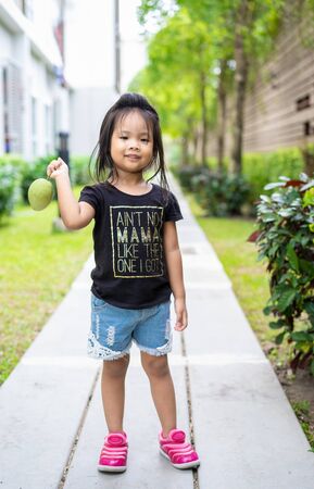 Little girl with a mango in her handの写真素材