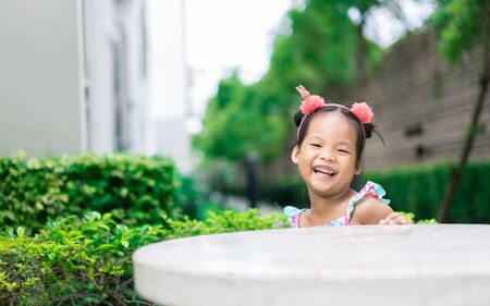 portrait of cute asian little girl sitting on table rock in the parkの写真素材